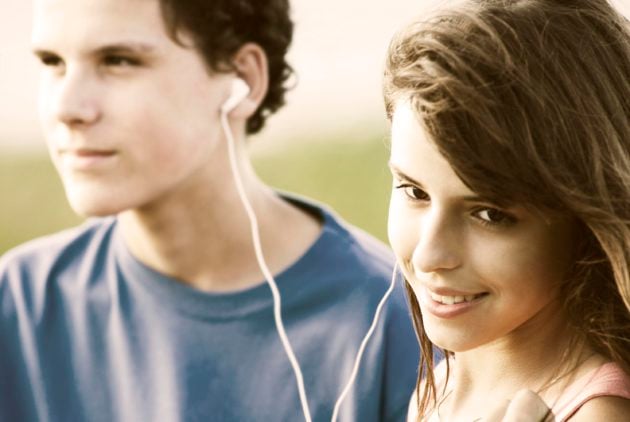 Teens sharing earphones, listening music outdoor.</span> <span class=