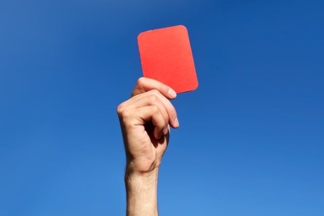 referee hands with red card on football field